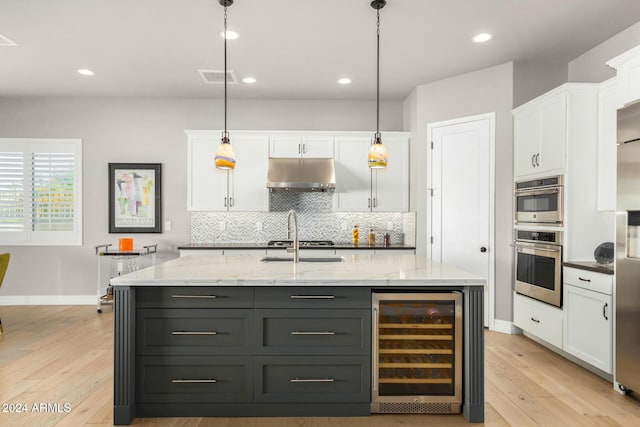 kitchen with wine cooler, white cabinetry, decorative light fixtures, and light wood-type flooring