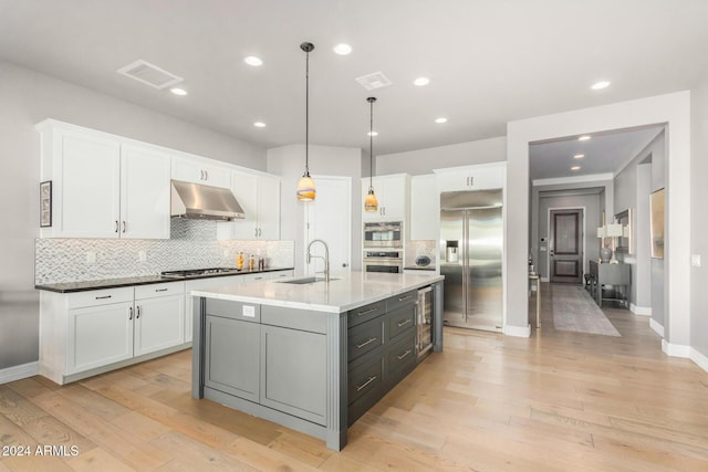 kitchen featuring white cabinetry, sink, stainless steel appliances, and decorative light fixtures