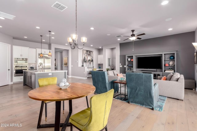 dining room featuring ceiling fan with notable chandelier, light hardwood / wood-style floors, and sink