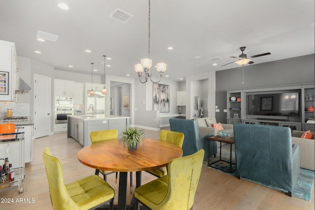 dining room featuring light hardwood / wood-style flooring, ceiling fan with notable chandelier, and sink