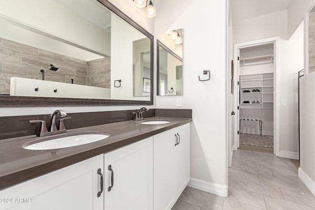 bathroom with tile patterned flooring, a tile shower, and vanity