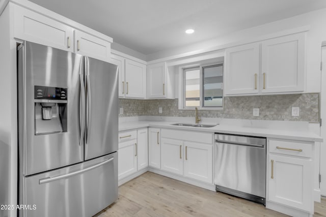 kitchen featuring stainless steel appliances, a sink, light countertops, white cabinetry, and light wood-style floors