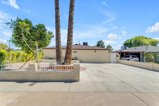 ranch-style house featuring a fenced front yard, stucco siding, and concrete driveway