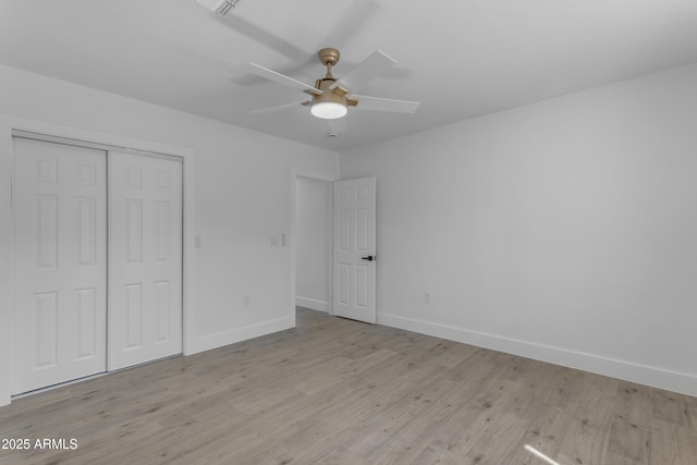 unfurnished bedroom featuring baseboards, wood finished floors, a closet, and ceiling fan