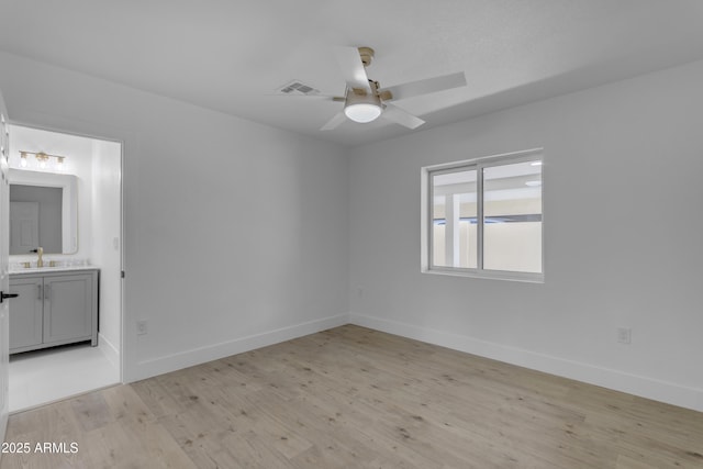 unfurnished room featuring ceiling fan, light wood-type flooring, baseboards, and a sink