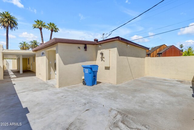 back of house featuring stucco siding, fence, and an attached carport