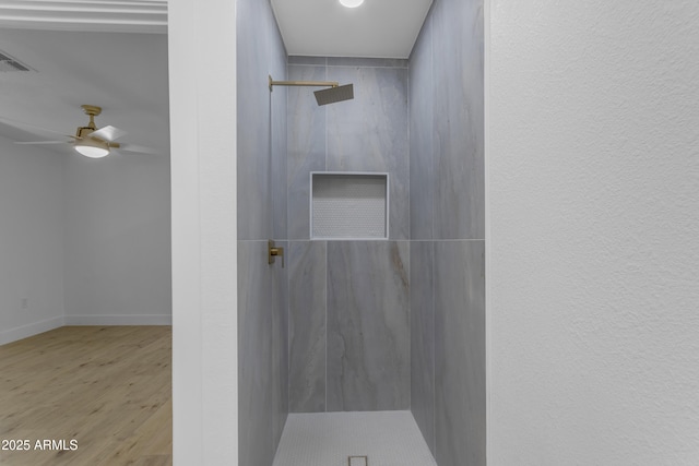 bathroom featuring a marble finish shower, wood finished floors, a ceiling fan, and baseboards
