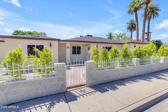 ranch-style house with a fenced front yard, stucco siding, and a gate