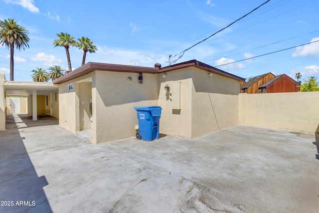 back of house featuring stucco siding, fence, and an attached carport