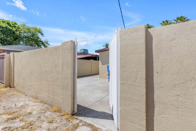 view of side of property with stucco siding, fence, and a patio area