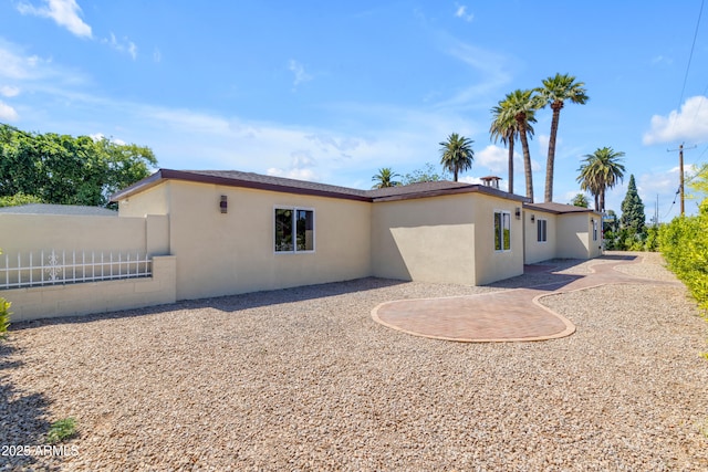back of house featuring stucco siding and fence
