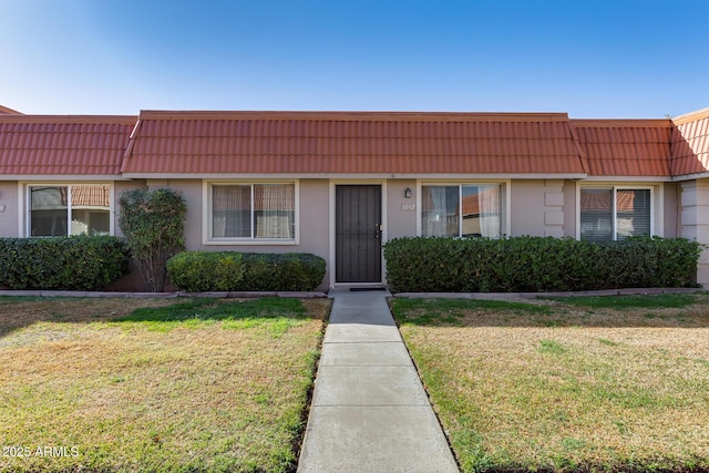 multi unit property with mansard roof, a front lawn, and a tile roof