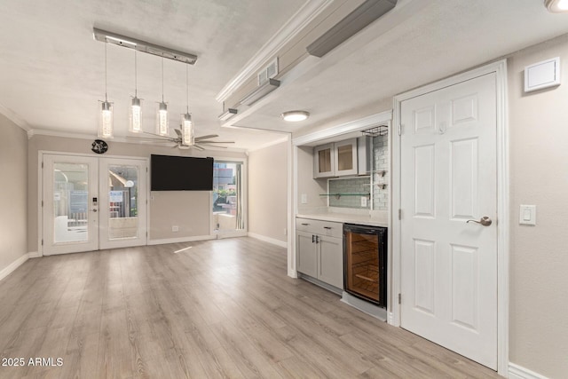 bar with beverage cooler, baseboards, ornamental molding, french doors, and light wood-type flooring