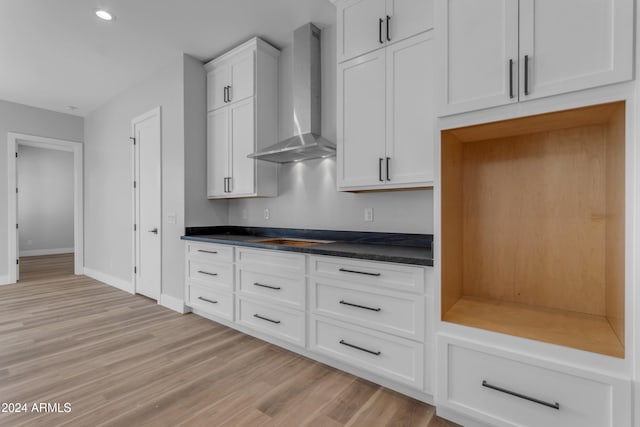 kitchen featuring white cabinets, stovetop, light hardwood / wood-style flooring, and wall chimney range hood