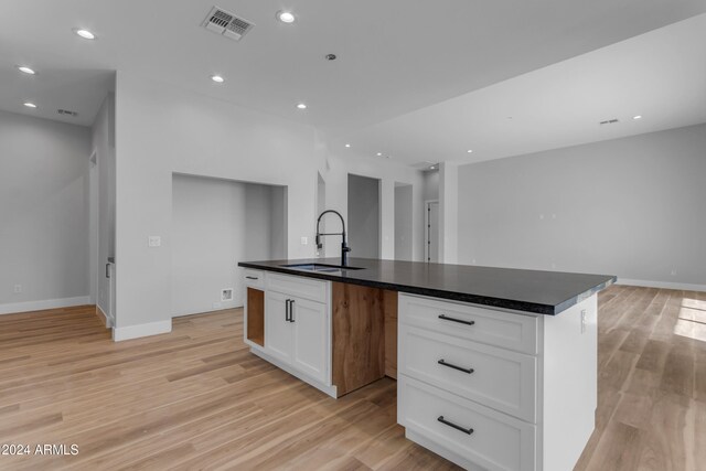 kitchen with light hardwood / wood-style flooring, sink, a center island with sink, and white cabinets