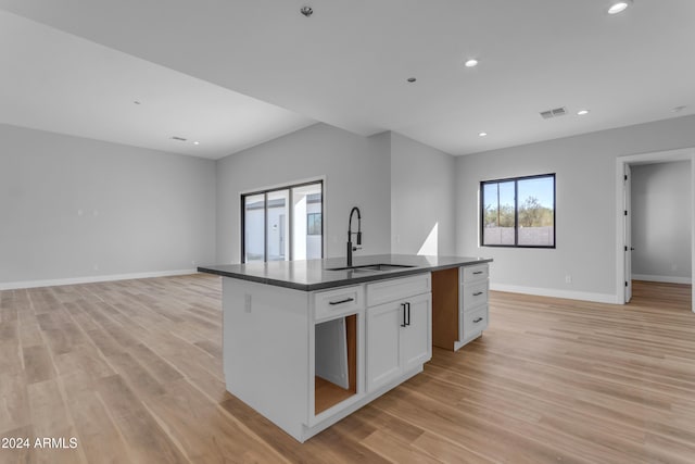 kitchen with white cabinetry, sink, an island with sink, and light hardwood / wood-style floors