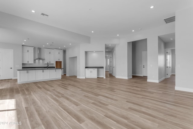 unfurnished living room featuring sink and light hardwood / wood-style flooring