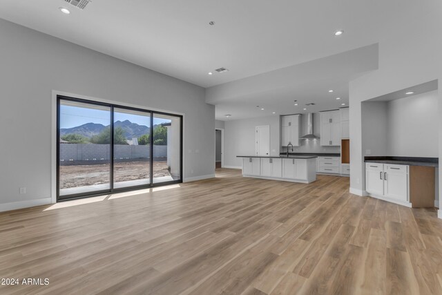 unfurnished living room with a mountain view, sink, and light wood-type flooring