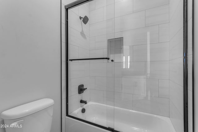 bathroom with combined bath / shower with glass door and toilet