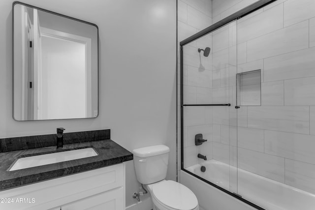 full bathroom featuring bath / shower combo with glass door, vanity, and toilet