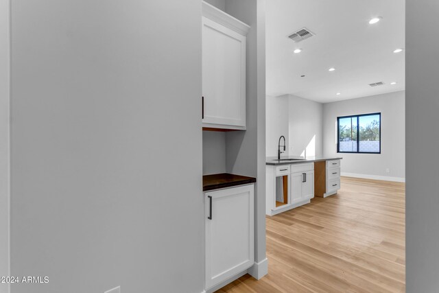 kitchen featuring light wood-type flooring, sink, and white cabinets