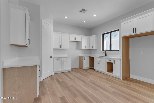 kitchen with sink, light hardwood / wood-style floors, and white cabinets