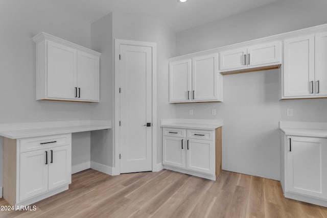 kitchen featuring white cabinetry, built in desk, and light hardwood / wood-style floors