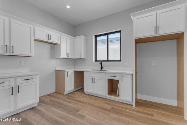 kitchen with white cabinetry, sink, and light hardwood / wood-style floors