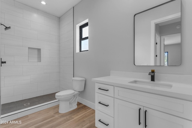 bathroom featuring vanity, hardwood / wood-style floors, toilet, and tiled shower