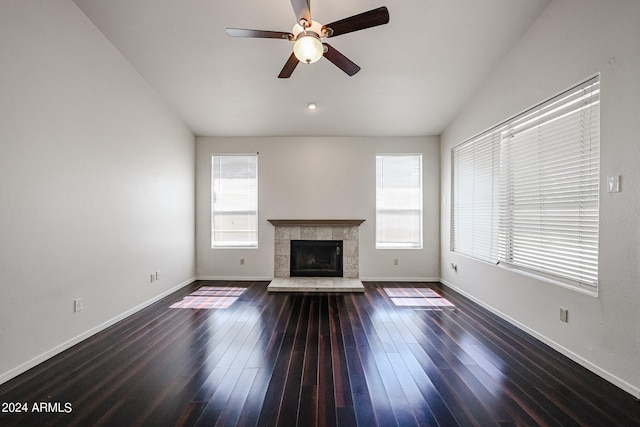 unfurnished living room with a fireplace, dark hardwood / wood-style floors, ceiling fan, and plenty of natural light