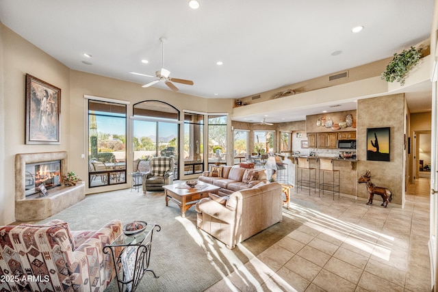 living room with ceiling fan, a fireplace, and light colored carpet