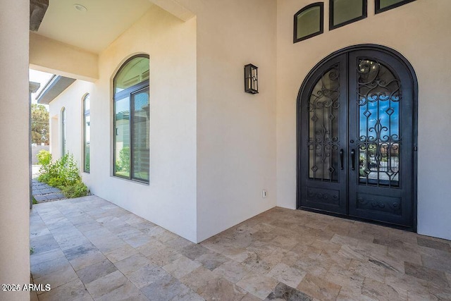 entrance to property with french doors, a patio area, and stucco siding