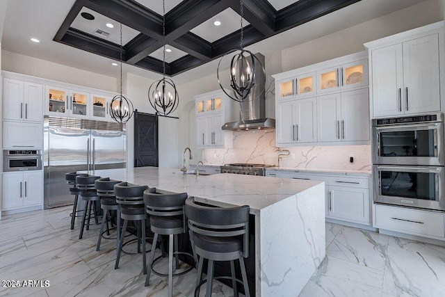 kitchen with stainless steel appliances, an island with sink, glass insert cabinets, and white cabinets