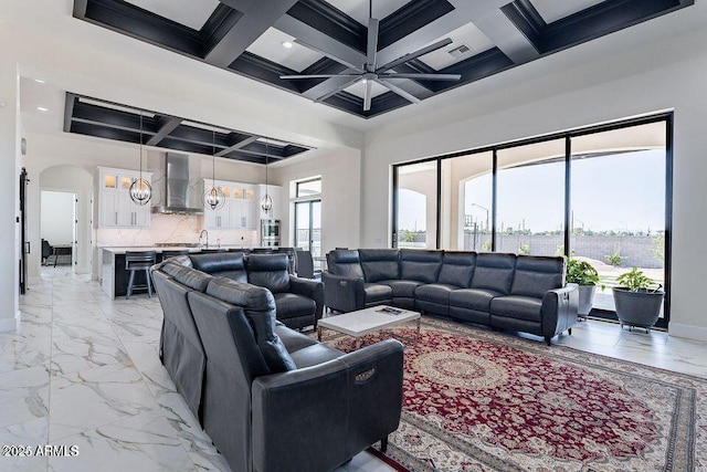 living room featuring marble finish floor, plenty of natural light, baseboards, and coffered ceiling