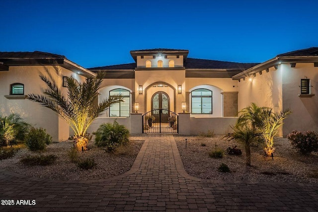 view of front facade with french doors, a gate, and stucco siding