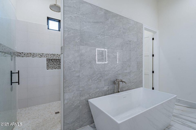 bathroom with a stall shower, marble finish floor, a freestanding bath, and tile walls