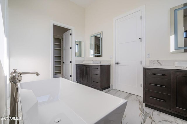 bathroom featuring a freestanding bath, marble finish floor, and two vanities