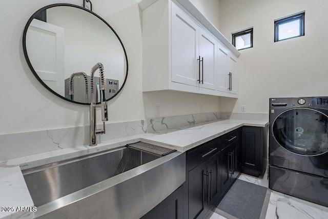 clothes washing area with cabinet space, washer / clothes dryer, marble finish floor, and a sink