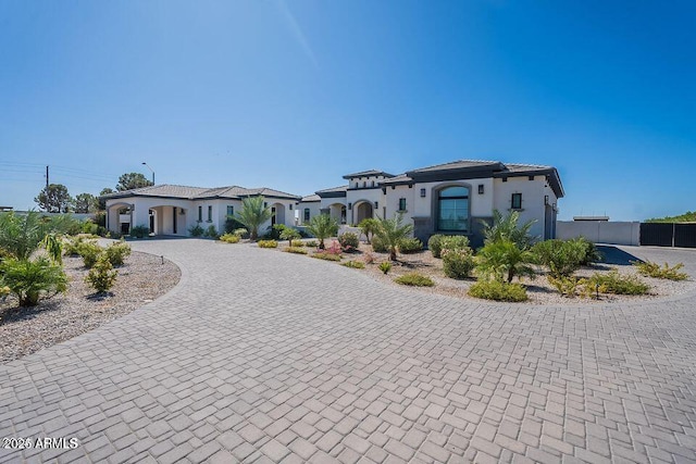 mediterranean / spanish-style house with a residential view, curved driveway, fence, and stucco siding