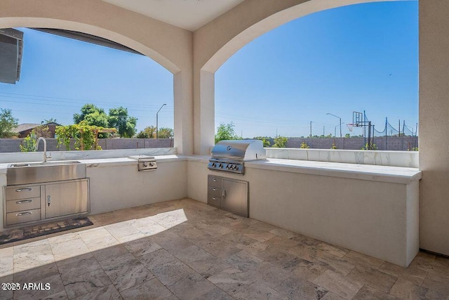 view of patio featuring fence, a sink, and area for grilling