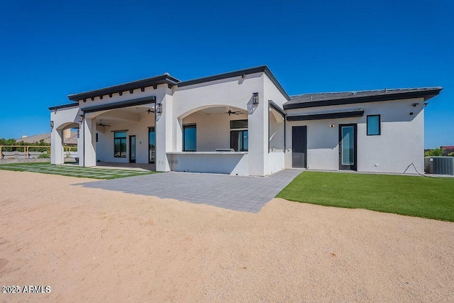 rear view of house featuring a ceiling fan, a patio, cooling unit, a yard, and stucco siding