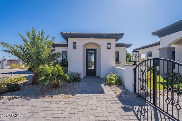 doorway to property featuring a gate, fence, and stucco siding