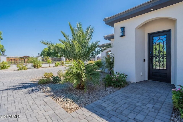 doorway to property with fence and stucco siding