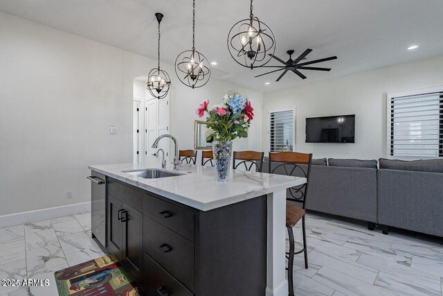 kitchen featuring marble finish floor, decorative light fixtures, open floor plan, a sink, and an island with sink