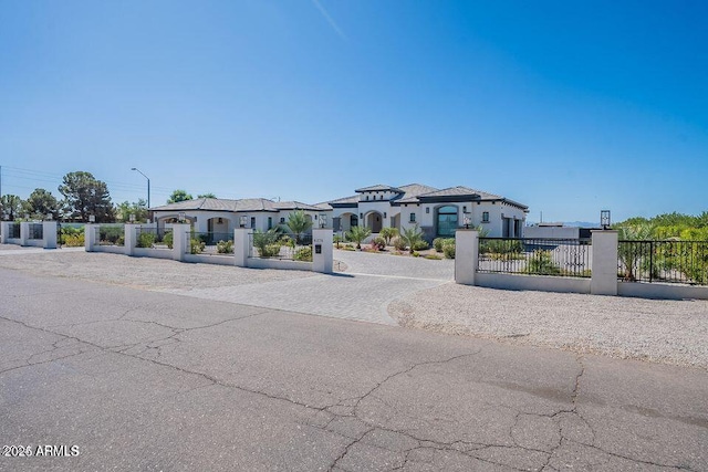 mediterranean / spanish-style house with a fenced front yard, a residential view, and decorative driveway