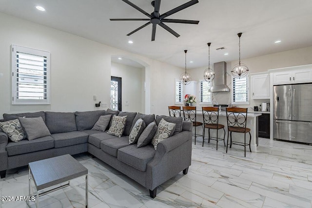 living area featuring arched walkways, ceiling fan, marble finish floor, and recessed lighting