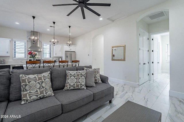 living area featuring arched walkways, marble finish floor, visible vents, and baseboards