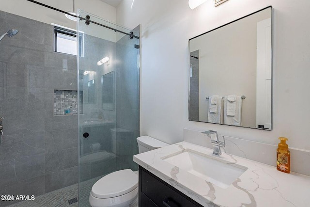 bathroom featuring toilet, a tile shower, and vanity