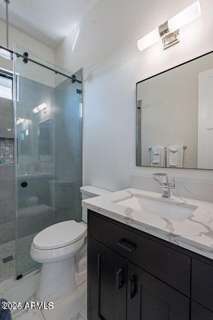 bathroom with a stall shower, vanity, and toilet