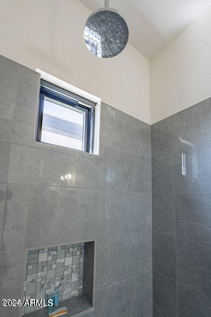 bathroom featuring vaulted ceiling and a tile shower